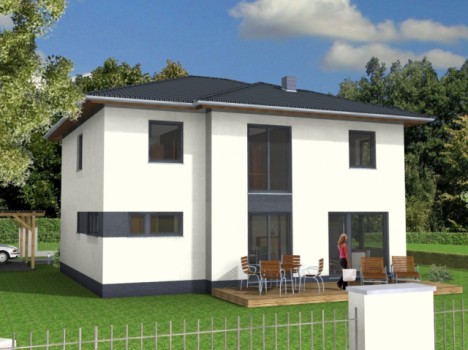 Ein modernes zweistöckiges weißes Haus, das exemplarisch für das Dresdner Massivhaus-Design steht, verfügt über ein dunkles Dach und eine Holzterrasse mit Sitzgelegenheiten im Freien. Eine Person steht auf der Terrasse, umgeben von grünen Bäumen und einem klaren blauen Himmel mit ein paar Wolken. Links ist teilweise ein Auto zu sehen.