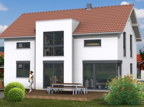 Ein modernes zweistöckiges Haus mit weißer Fassade und rotem Ziegeldach ist ein beeindruckendes Beispiel für den Dresdner Massivhausbau. Große Fenster dominieren die Vorderseite und lassen natürliches Licht ins Innere. Eine Frau steht auf einer Holzterrasse mit einem Picknicktisch, während blühende Büsche den Rasen schmücken.